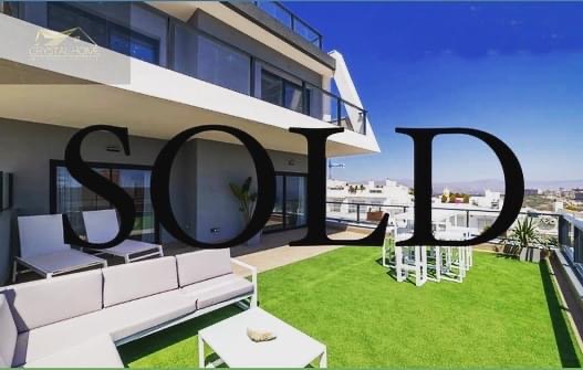 Nowoczesny apartament z tarasem na dachu, sztuczna trawa, meble ogrodowe, widok na miasto w oddali, napis SOLD na zdjęciu.