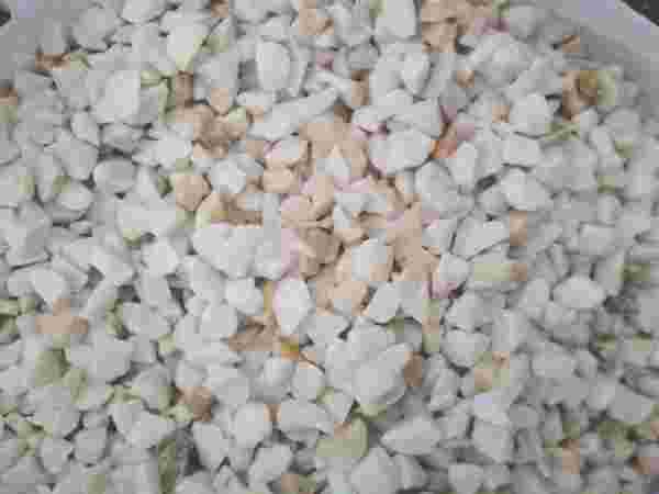 Białe i beżowe kruszywo kamienne o nieregularnych kształtach, wypełniające całą klatkę.