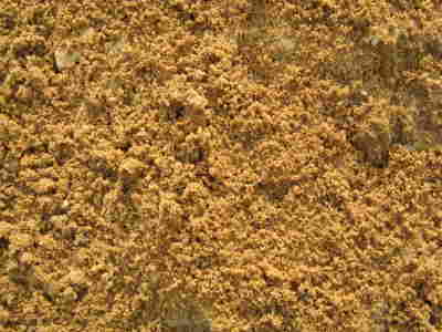 Jasnobrązowy piasek kwarcowy o drobnej granulacji, tworzący jednolitą teksturę. Widoczne niewielkie grudki i nierówności powierzchni.