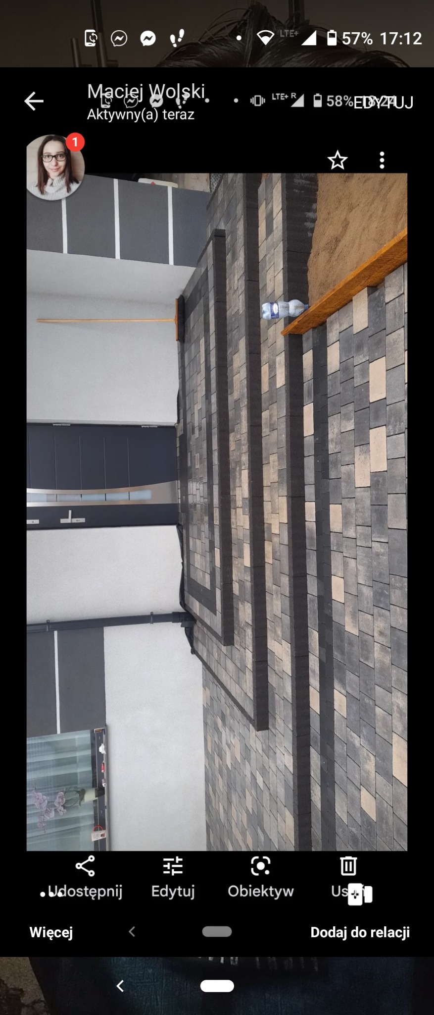 Świeżo ułożona, wielobarwna kostka brukowa na posesji, z widocznym fragmentem elewacji budynku i butelką wody stojącą na krawędzi.