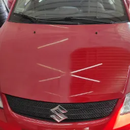 Czerwony samochód Suzuki SX4 przed myciem. Widoczne ślady brudu na masce, które zostaną usunięte.