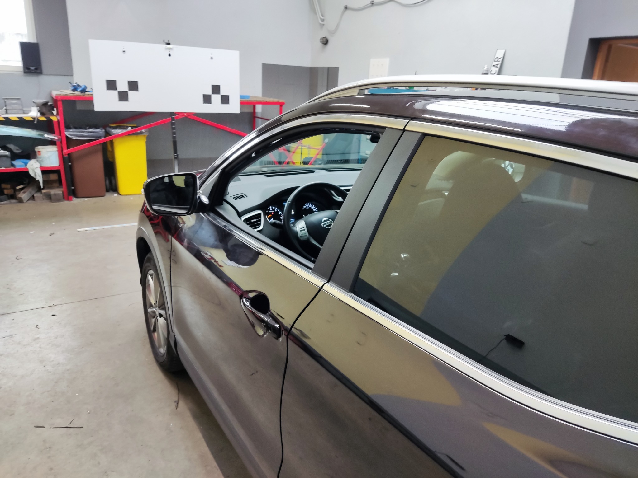 Samochód w warsztacie podczas ustawiania geometrii kół, widoczny celownik do ustawiania zbieżności.