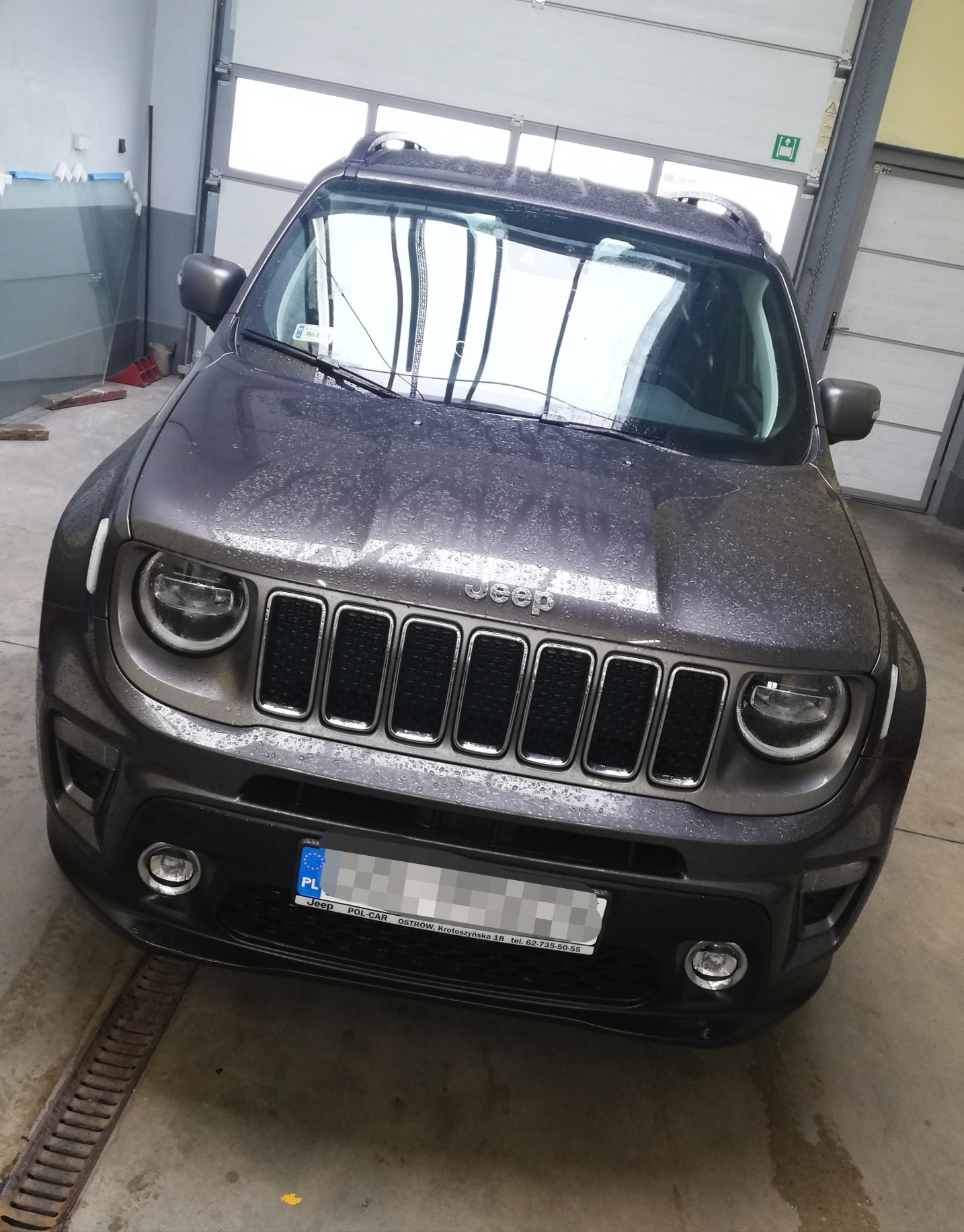 Szary Jeep Renegade z widocznymi kroplami wody na karoserii, zaparkowany w garażu z widocznymi szybami na boku.