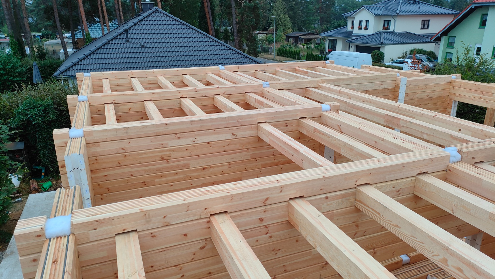 Konstrukcja domu szkieletowego w trakcie budowy w Białymstoku, widoczne drewniane ściany i elementy stropu z izolacją, w tle zabudowa jednorodzinna.