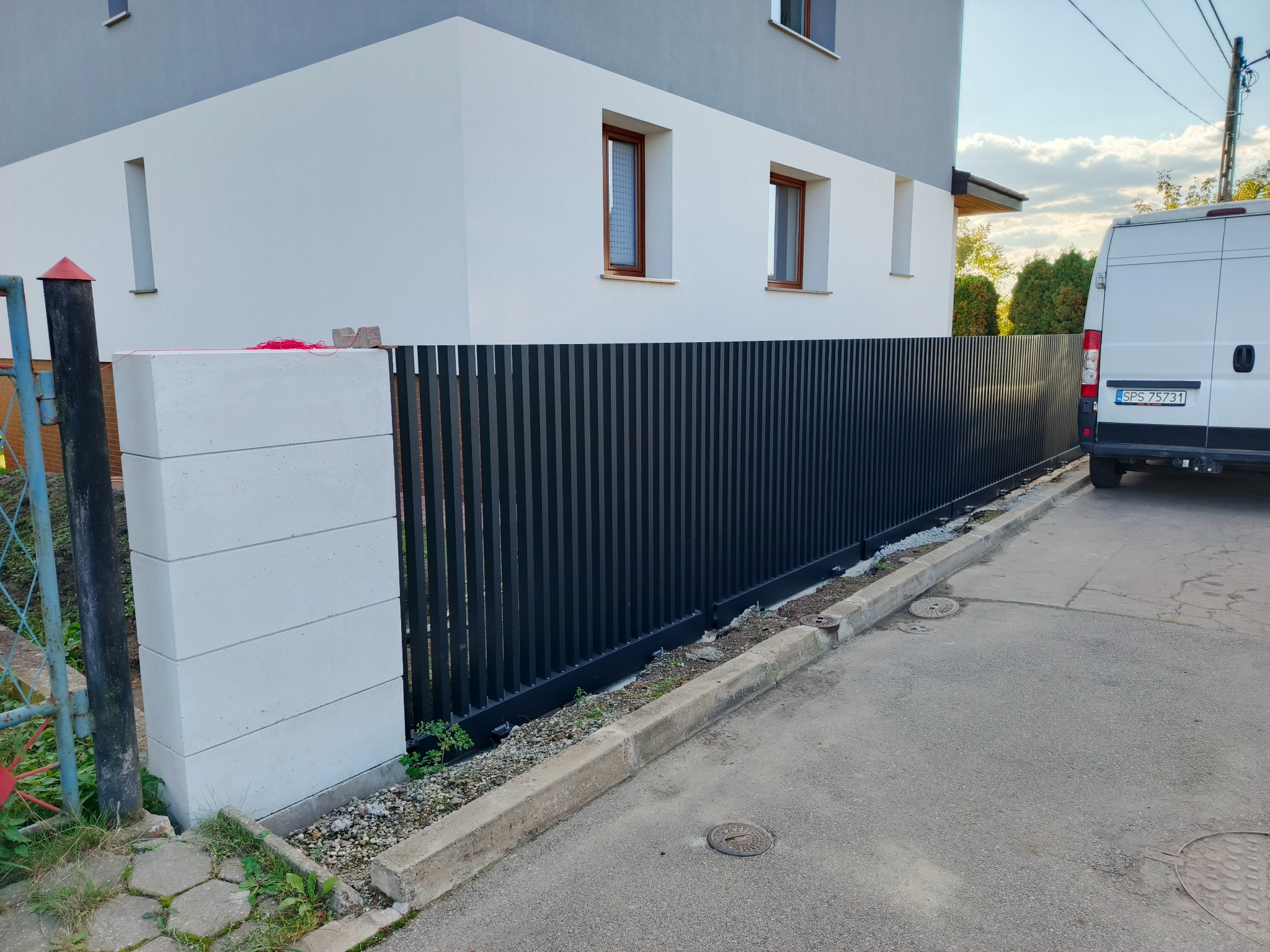 Nowoczesne ogrodzenie panelowe w kolorze antracytowym z betonowymi słupkami, Pawłowice. Minimalistyczny design, dopasowany do architektury budynku.