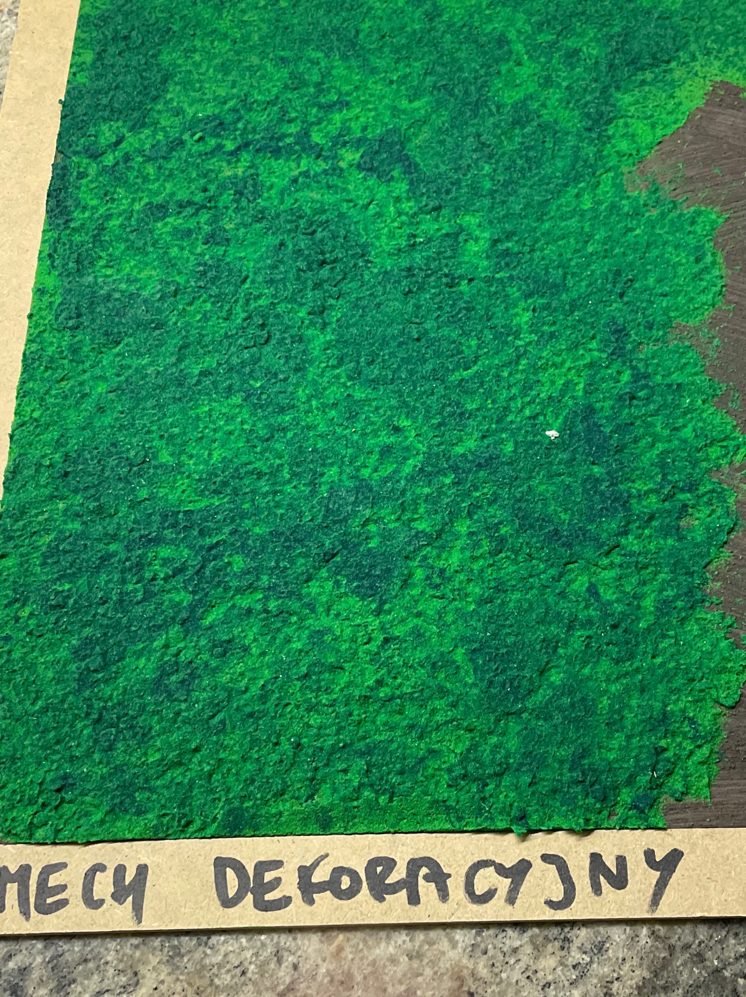 Zielony mech dekoracyjny na płycie, próbka materiału prezentowana w Głogowie.