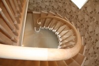 Spiralne, drewniane schody z zaokrągloną poręczą, widok z góry, tapeta w tle.