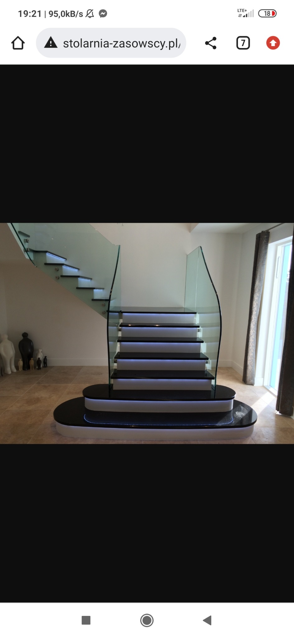 Nowoczesne schody z podświetleniem LED i szklaną balustradą, widoczne figurki dekoracyjne na podłodze.