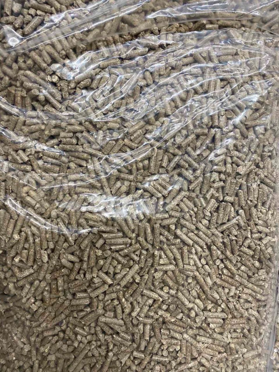 Przezroczysty worek wypełniony szarym, drobnym granulatem opału, widoczne zagniecenia i załamania folii.