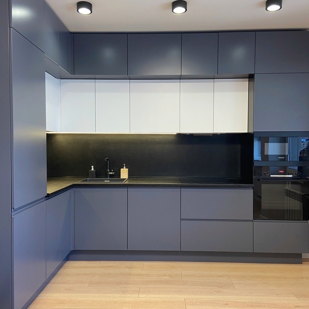 Nowoczesna kuchnia z szarymi szafkami dolnymi i białymi górnymi, czarnym blatem i panelem nad blatem, oświetleniem punktowym i drewnianą podłogą.