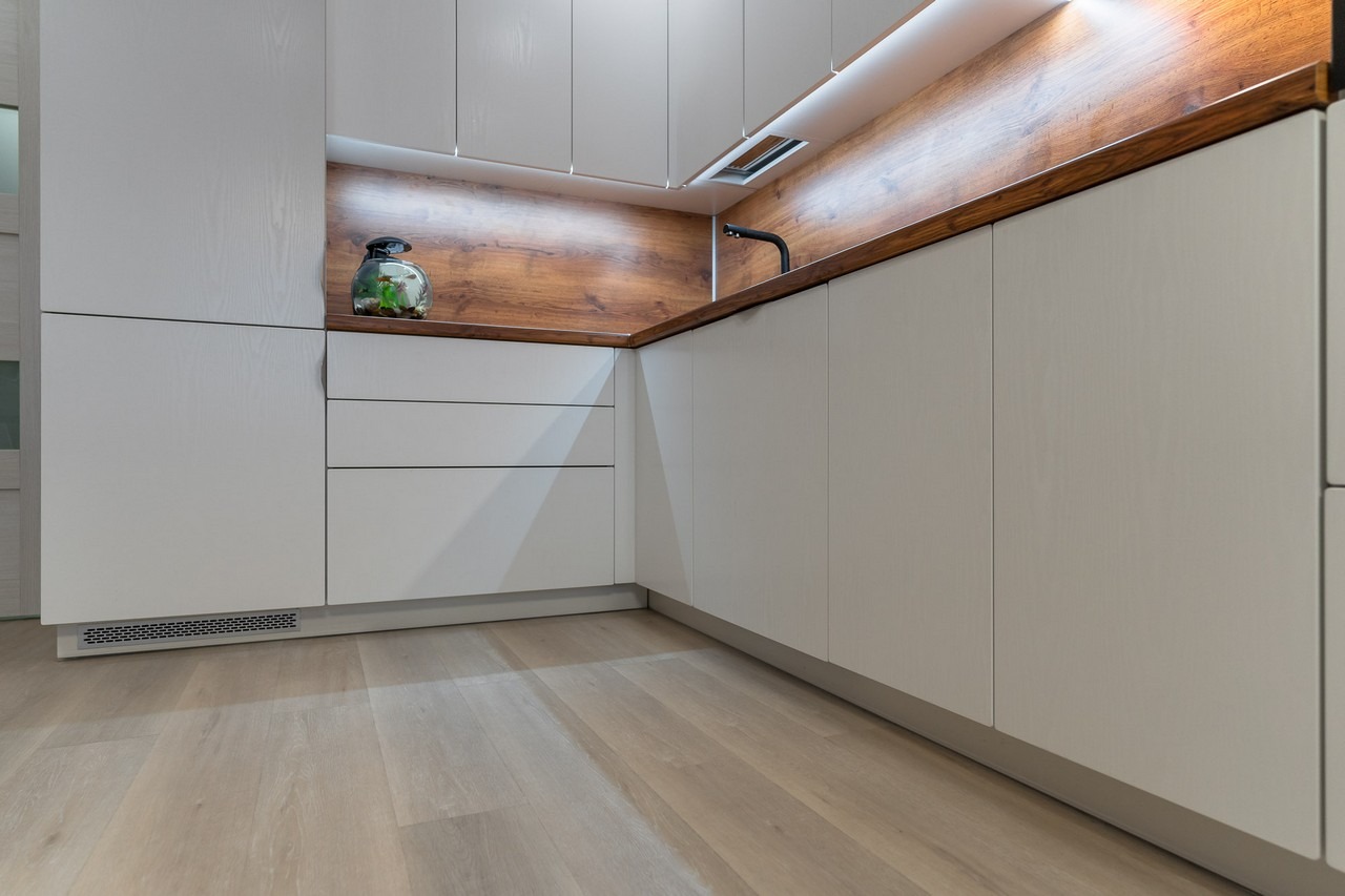 Nowoczesna kuchnia z białymi frontami i drewnianym blatem w Łodzi, z akcentem w postaci oświetlenia LED i dekoracyjnego akwarium.