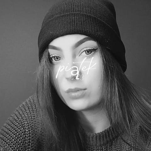 Portret młodej kobiety w czapce, z delikatnym makijażem oczu, w swetrze, na szarym tle, w czerni i bieli.