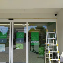 Montaż kamery monitoringu przy wejściu do sklepu Stokrotka, widoczna drabina i przewód elektryczny.