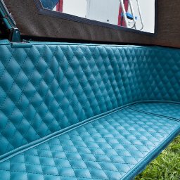 SK PARTS SPÓŁKA Z OGRANICZONĄ ODPOWIEDZIALNOŚCIĄ - Turkusowa, pikowana tapicerka siedziska w pojeździe, widoczna z bliska. Staranne przeszycia w romby, gładka powierzchnia, fragment otoczenia w tle.