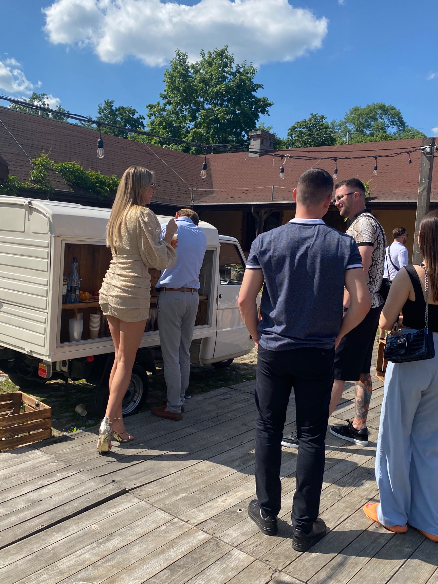 Mobilny bar w stylu retro na zewnątrz, obsługa gości podczas wydarzenia plenerowego w słoneczny dzień.