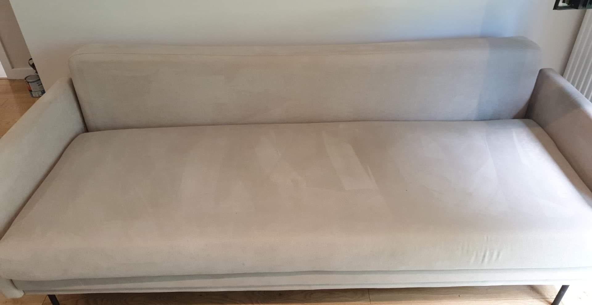 Jasna kanapa z widocznymi śladami czyszczenia na siedzisku, ukazująca efekt usługi.