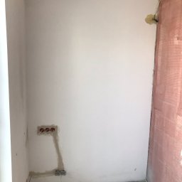 Crado - Ściana w trakcie prac przygotowawczych: gładź wokół puszek elektrycznych, fragment ściany z widocznym ociepleniem, surowa podłoga, narożnik pokoju w trakcie remontu.