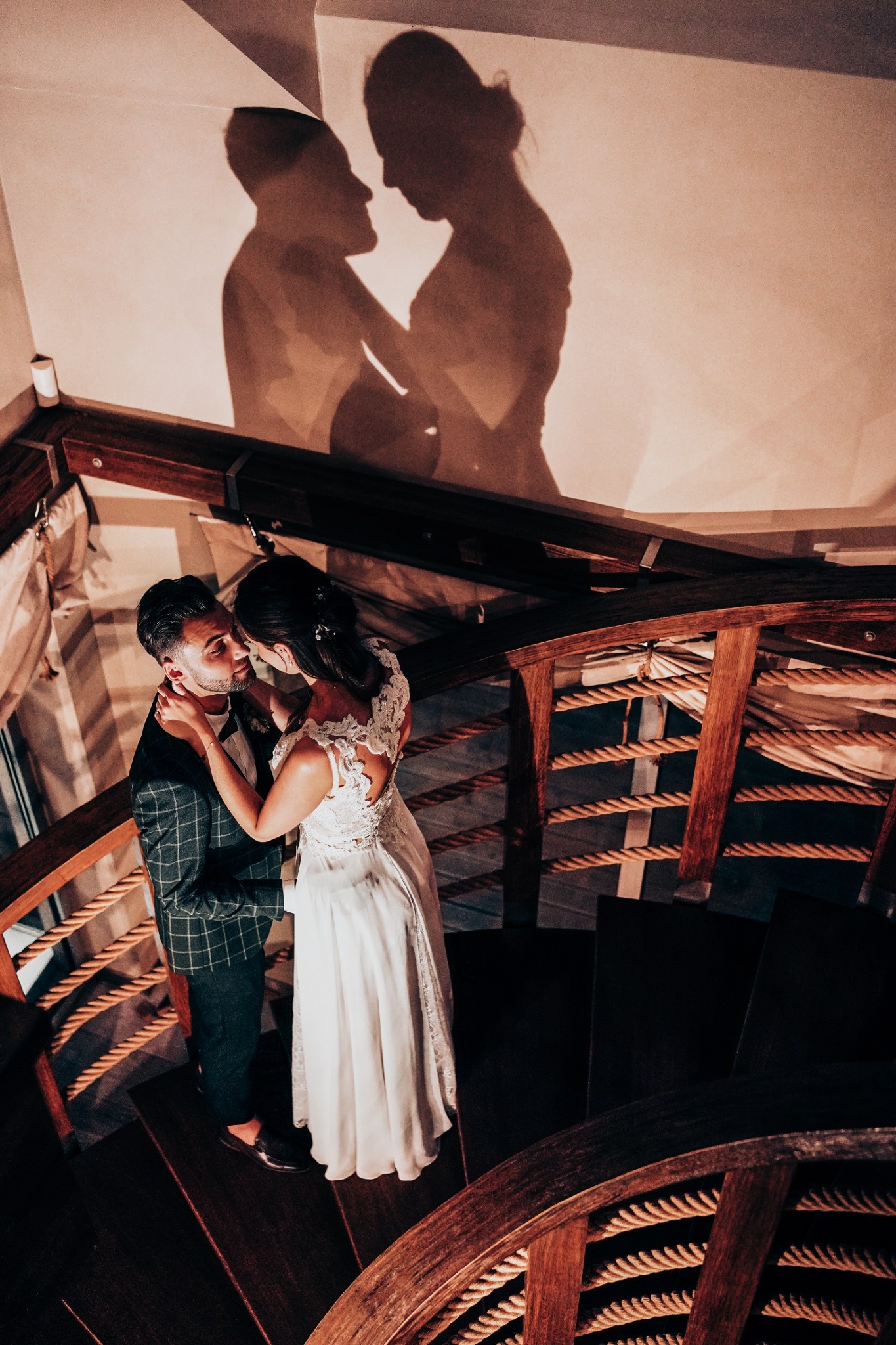 Para młoda na drewnianych schodach spiralnych, ujęcie z góry, cień zakochanych na ścianie.