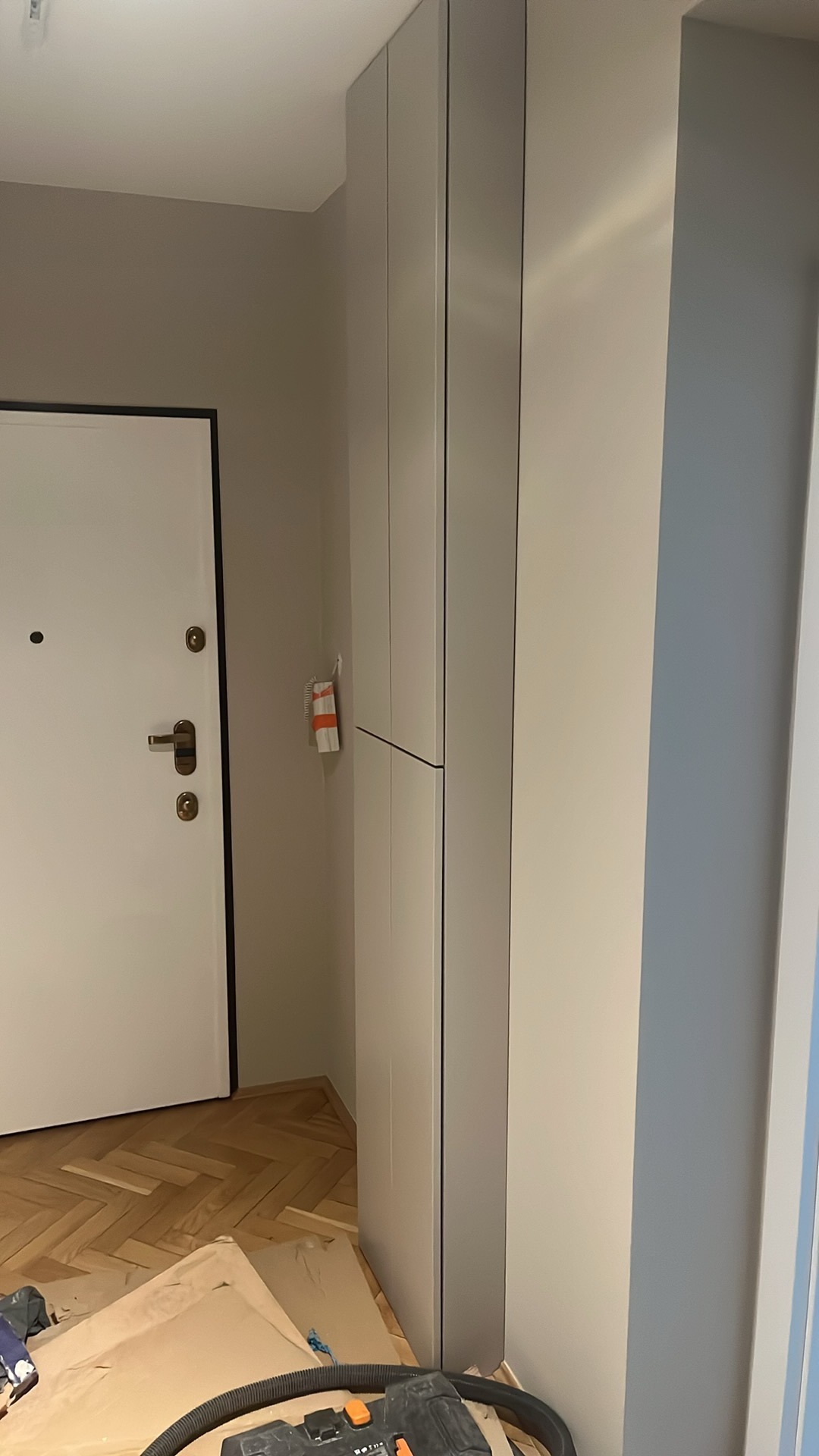 Montaż szafy wnękowej w przedpokoju, widoczny odkurzacz przemysłowy i zabezpieczenia podłogi.