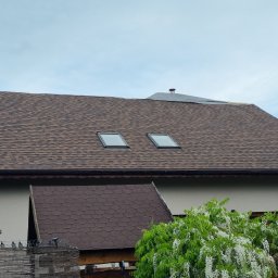 Pokrycia Dachowe Paweł Czarnuch - Dach pokryty brązowym gontem bitumicznym z dwoma oknami dachowymi. Fragment dachu w trakcie prac wykończeniowych. Widoczny komin i fragment elewacji budynku.