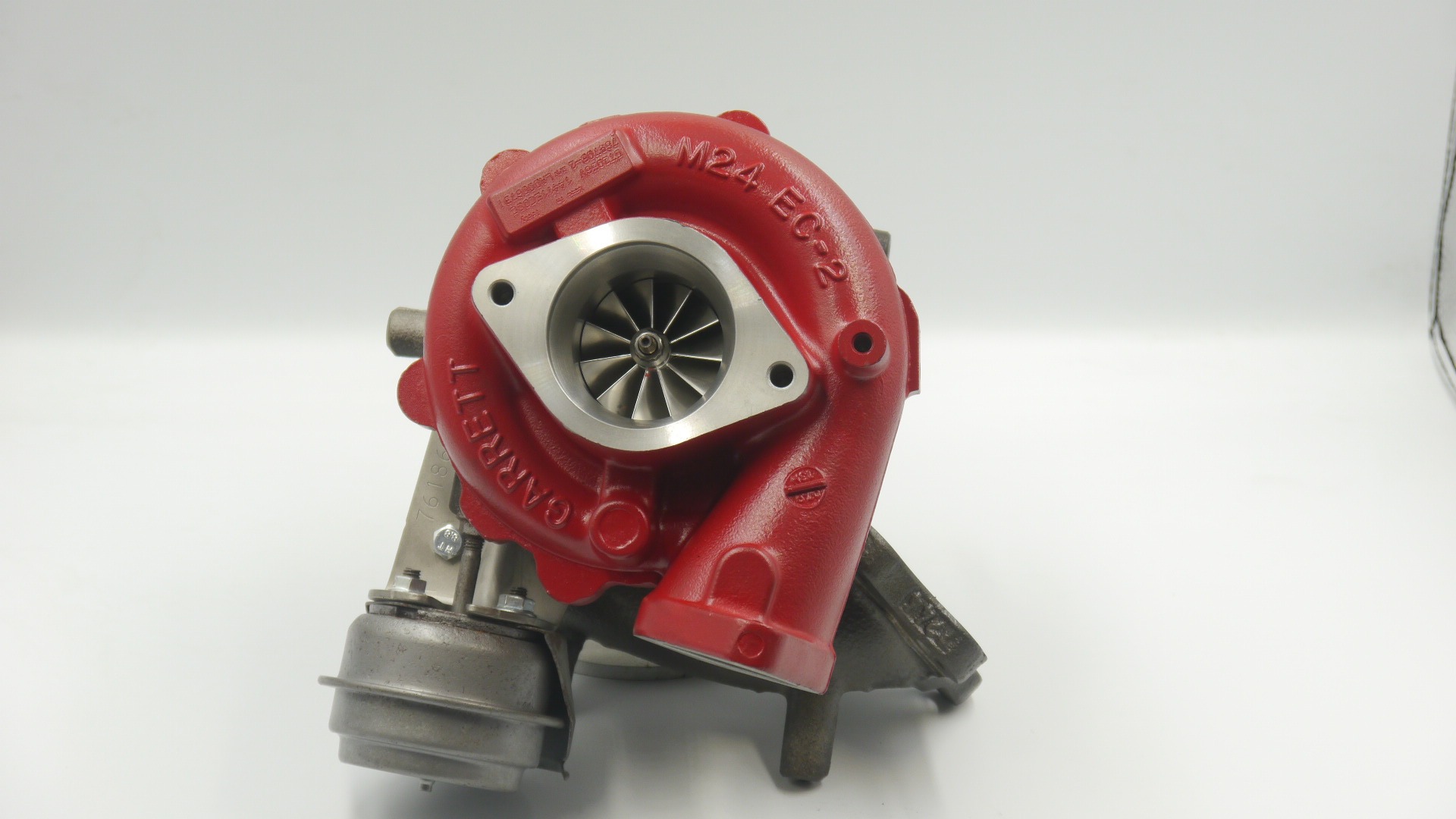 Czerwona turbosprężarka Garrett M24 EC-2 z widocznymi łopatkami wirnika na białym tle.