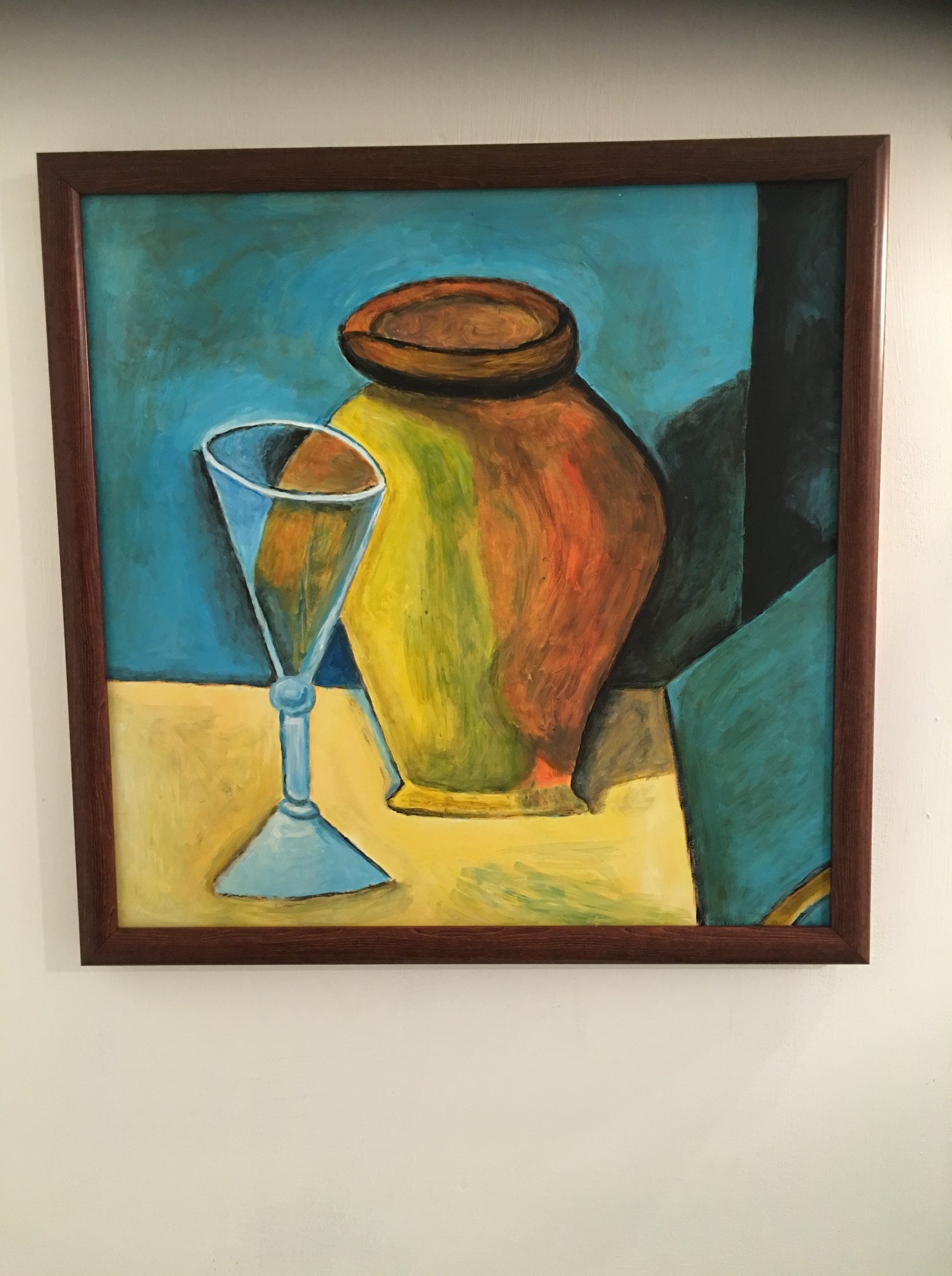 Obraz olejny w brązowej ramie przedstawiający martwą naturę z wazonem i kielichem na żółtym stole, namalowany w Plewiskach. Kolory są żywe, a tło ma odcienie niebieskiego i zielonego.