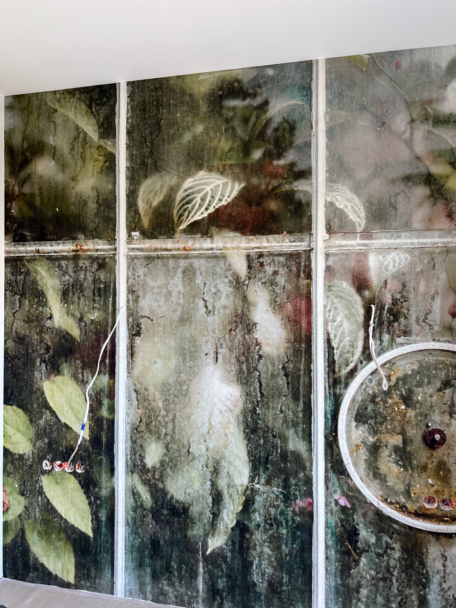 Fotorealistyczna tapeta imitująca starą szklarnię z roślinami, widoczne kable elektryczne i element dekoracyjny w kształcie koła