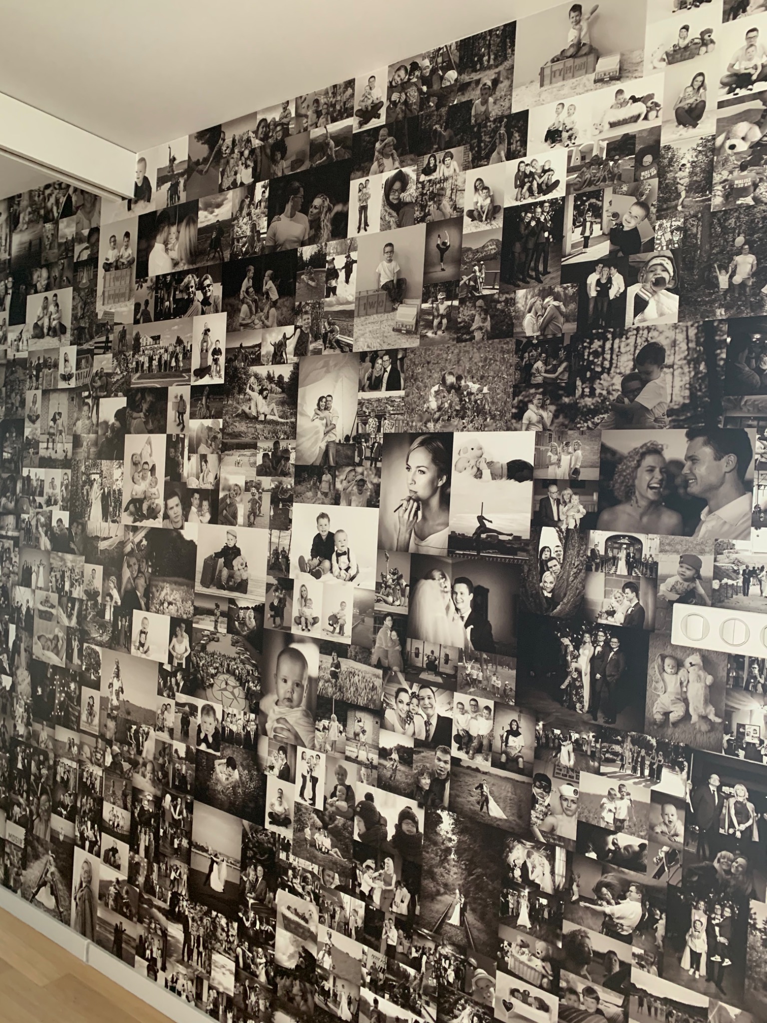 Ściana pokryta czarno-białymi fotografiami o różnej tematyce, tworząc kolaż rodzinnych wspomnień.
