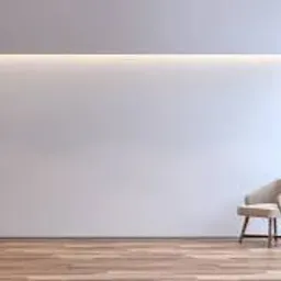 Minimalistyczne wnętrze w Sieniawie: gładka, biała ściana z subtelnym oświetleniem LED, drewniana podłoga i fotel w rogu. Nowoczesny design, jasne kolory.