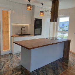 MEBLE GAL Tadeusz Gal - Nowoczesna kuchnia z białymi, lakierowanymi frontami, drewnianym blatem i wyspą, oświetleniem punktowym i marmurkową podłogą.