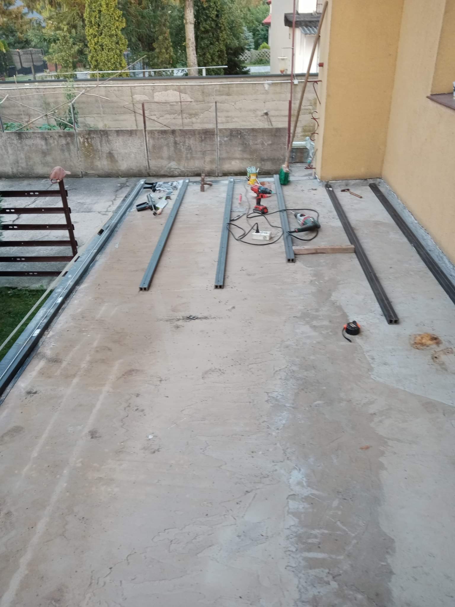 Przygotowanie konstrukcji metalowej w Sochaczewie: spawarka, wiertarka i profile stalowe leżą na betonowej posadzce, widoczne narzędzia i elementy w trakcie montażu.