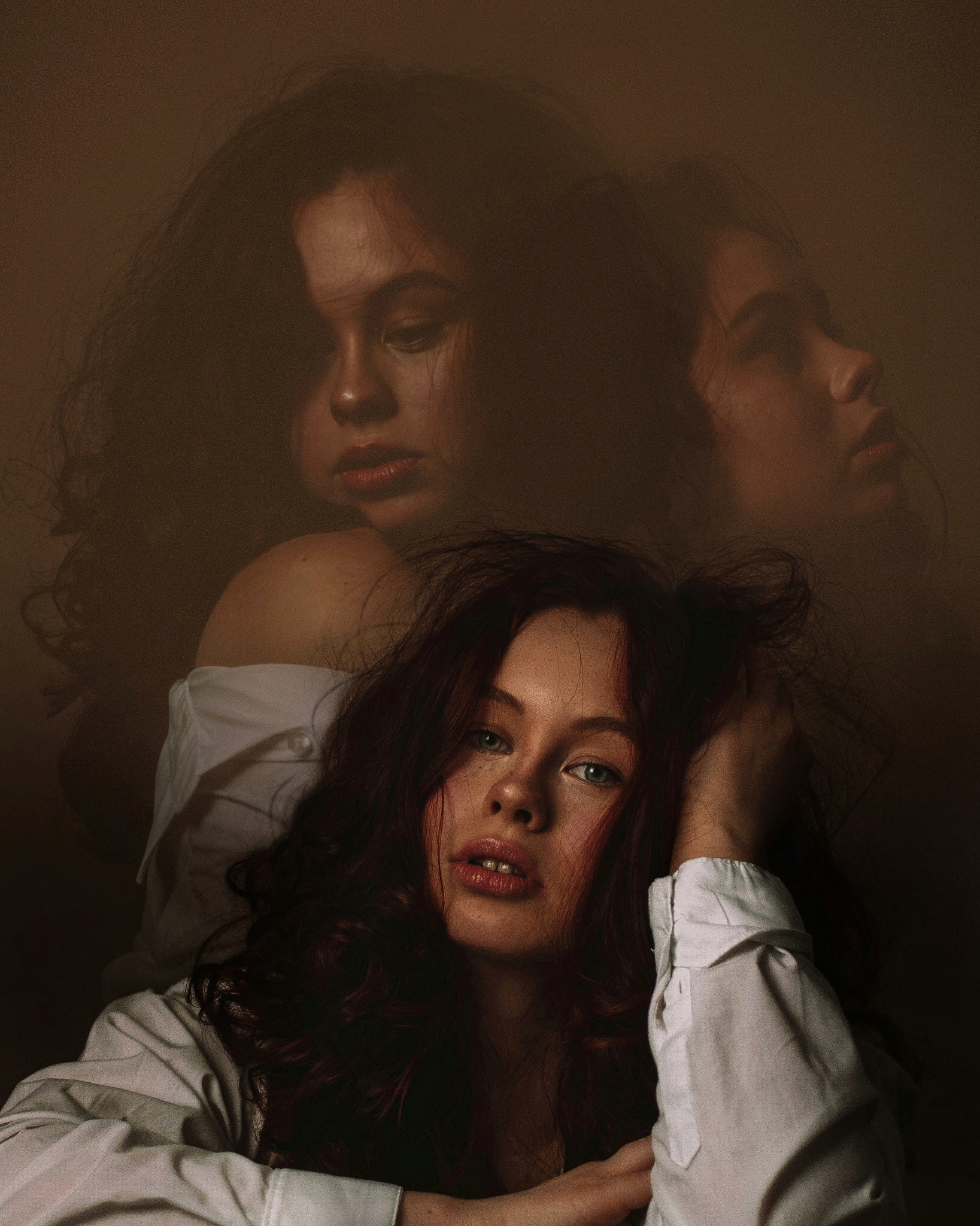 Portret kobiety z rozpuszczonymi, ciemnymi włosami i delikatnym makijażem, z efektem podwójnej ekspozycji na brązowym tle.