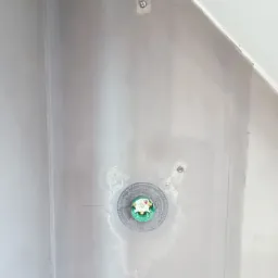 Ściana przygotowana do malowania z widocznymi śladami po szpachlowaniu i zamontowanym gniazdkiem elektrycznym. Widoczne linie pomocnicze na ścianie.