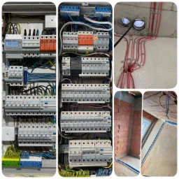 Rozdzielnice elektryczne z zabezpieczeniami, licznikiem i okablowaniem oraz fragmenty instalacji elektrycznej w surowym stanie, widoczne przewody przymocowane klamrami do sufitu i ściany.