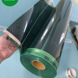 FOLIE GRZEWCZE, MATY -  Arkadiusz Zawadzki - Rolka przezroczystej folii grzewczej z czarnym wzorem kropek, trzymana w dłoni, widoczne oznaczenia CE i RoHS na krawędzi folii.