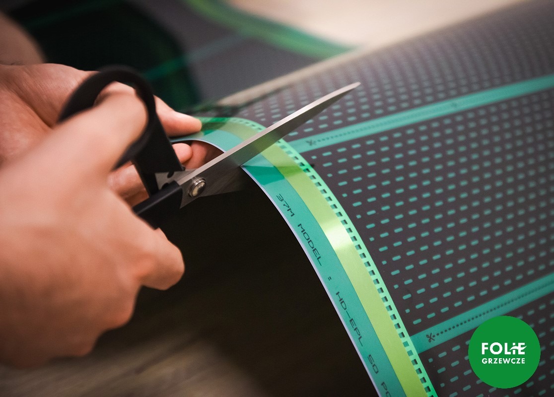 Cięcie nożyczkami folii grzewczej z widocznym modelem HD-EPL 50 PC 37M.