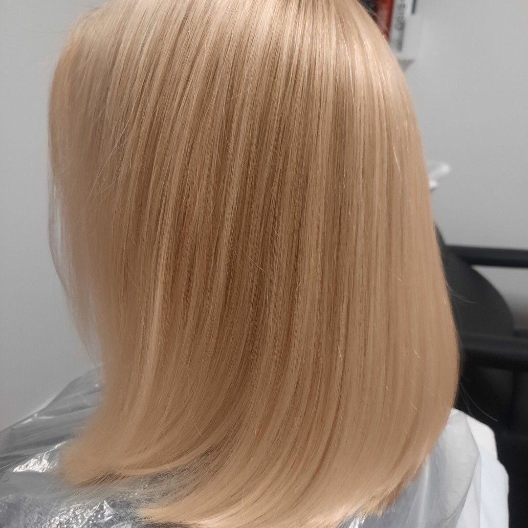 Blond włosy klientki po koloryzacji, proste, do ramion, w chłodnym odcieniu blondu, widok z tyłu, delikatny połysk.