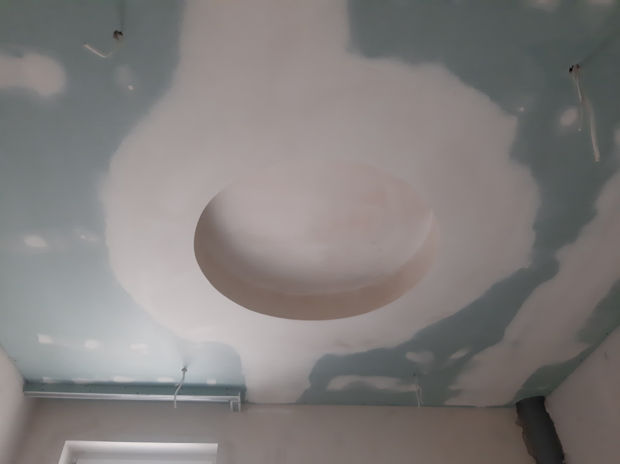 Niedokończony sufit z płyt kartonowo-gipsowych z okrągłym wgłębieniem, widoczne ślady szpachlowania i wystające kable.