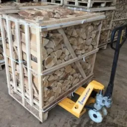 Klatka z drewnem opałowym, pocięte kawałki ułożone równo, transportowane w Wierzycach wózkiem paletowym.