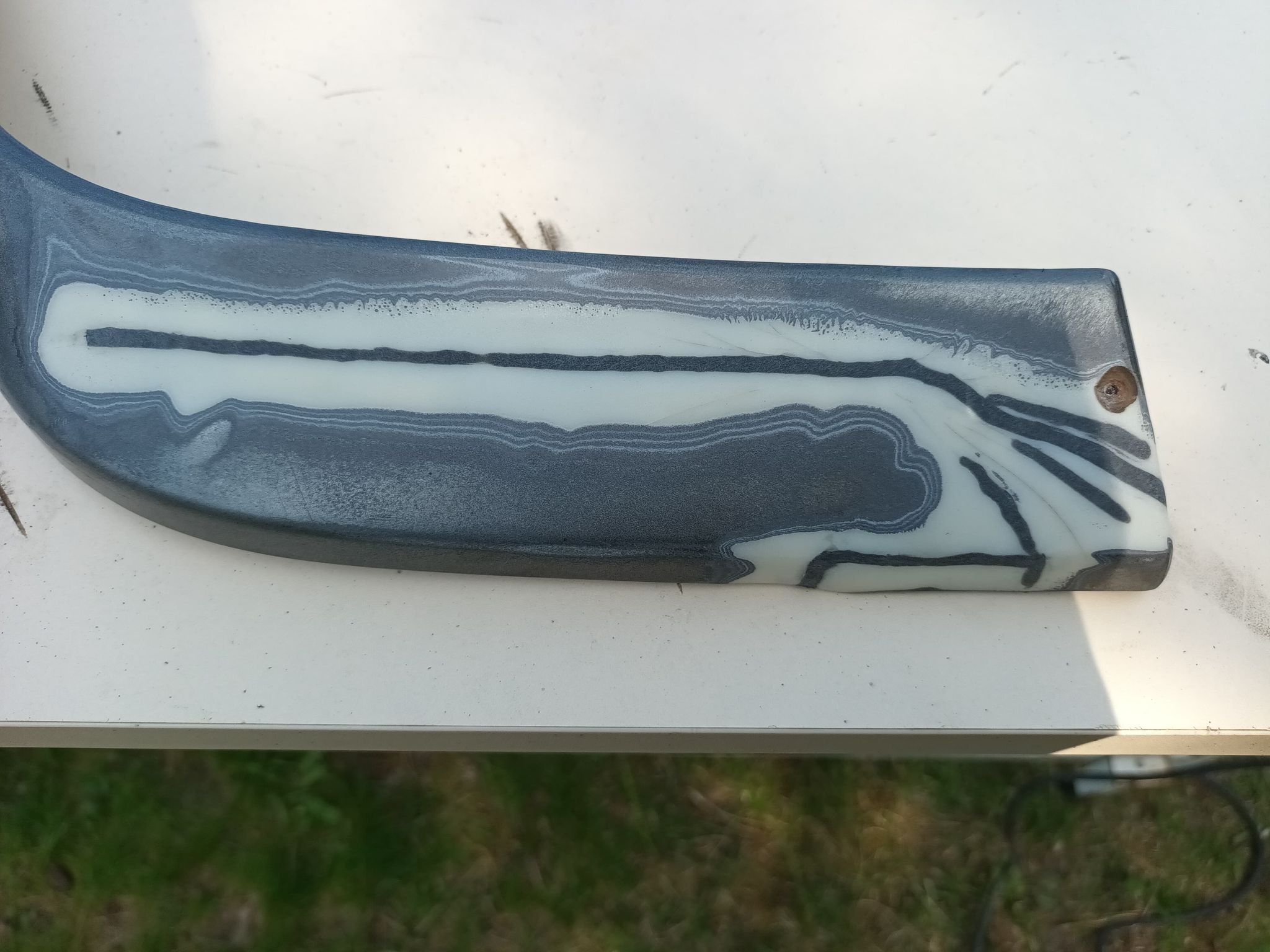 Element konstrukcyjny po procesie napawania, widoczne warstwy materiału o różnej twardości i kolorze, ślad po obróbce skrawaniem.