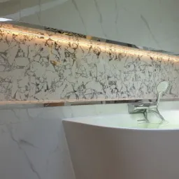 Nowoczesna łazienka z wolnostojącą wanną, armaturą chromowaną i podświetlaną ścianą z marmurowymi płytkami.