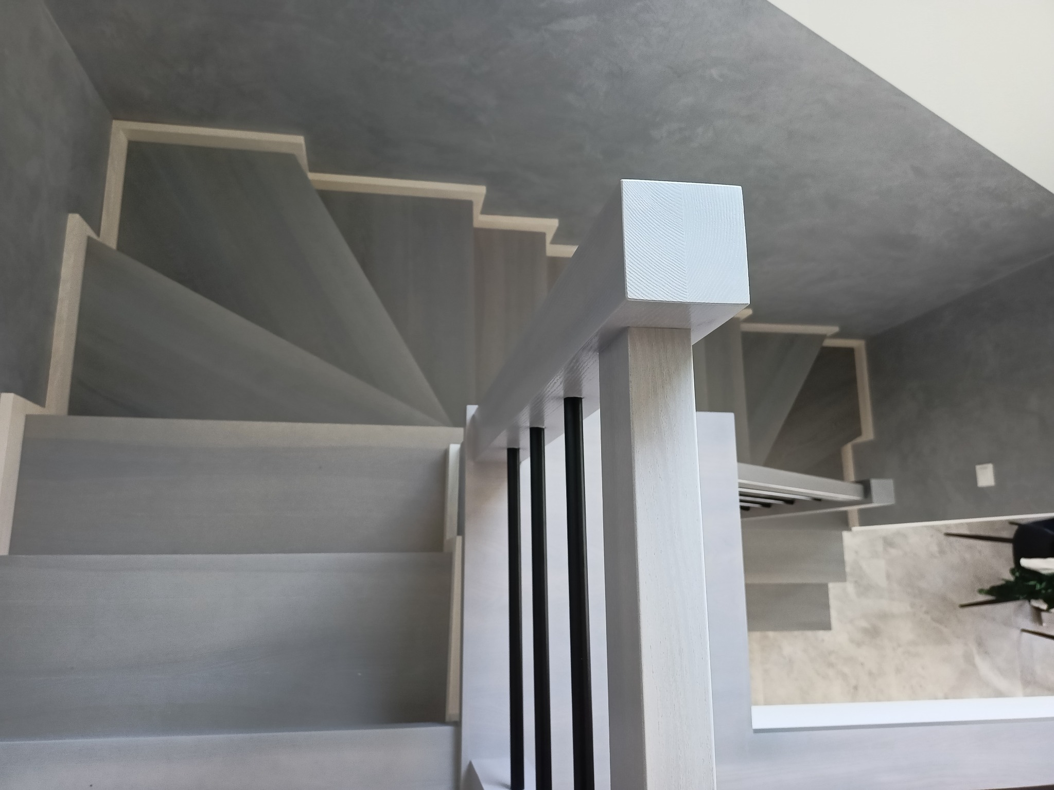 Nowoczesne schody drewniane z szarymi stopniami i białą balustradą z czarnymi elementami, widok z góry.