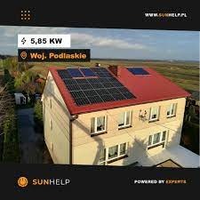 Dom jednorodzinny z czerwoną dachówką i zamontowaną instalacją fotowoltaiczną o mocy 5,85 kW w województwie podlaskim, widok z góry, z logo firmy Sunhelp w dolnym lewym rogu.