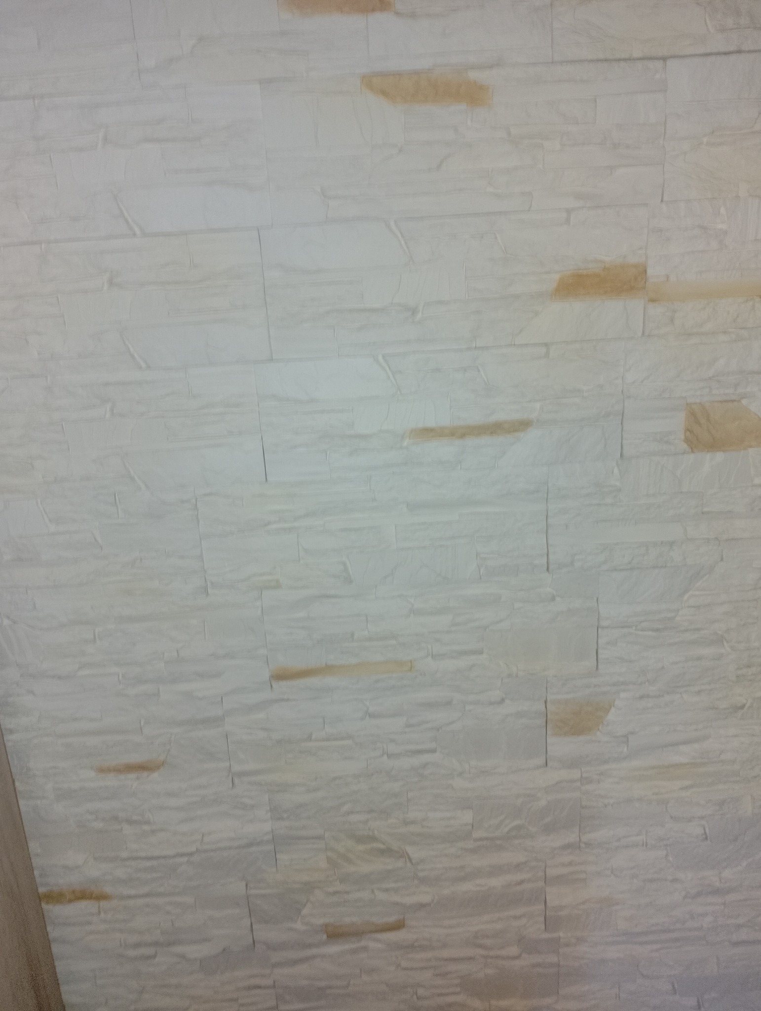 Ściana wykończona panelami imitującymi białą cegłę z delikatnymi akcentami beżu.