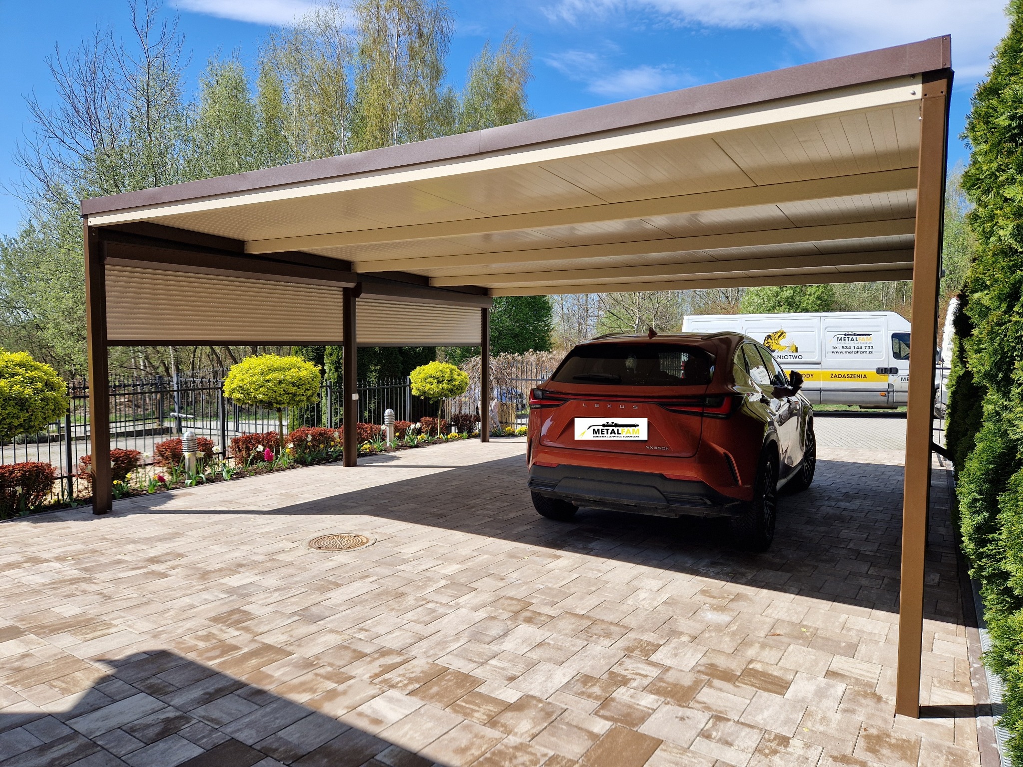 Metalowa pergola w kolorze brązowym, zadaszenie nad miejscem parkingowym dla samochodu Lexus NX350h, kostka brukowa na podjeździe, w tle bus firmy MetalFam z reklamą zadaszeń.
