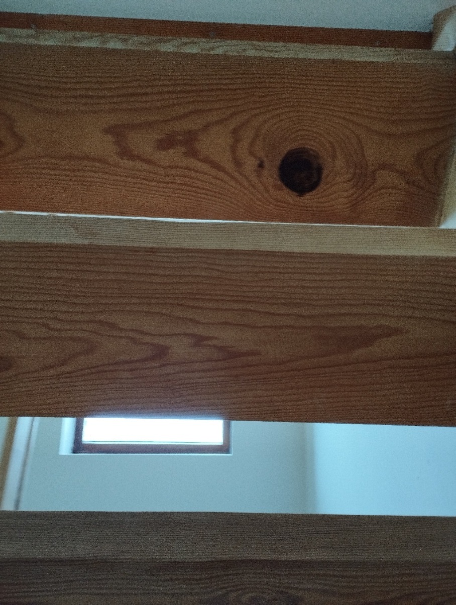 Fragment drewnianych schodów z widocznym oknem w tle, ujęcie z dołu.