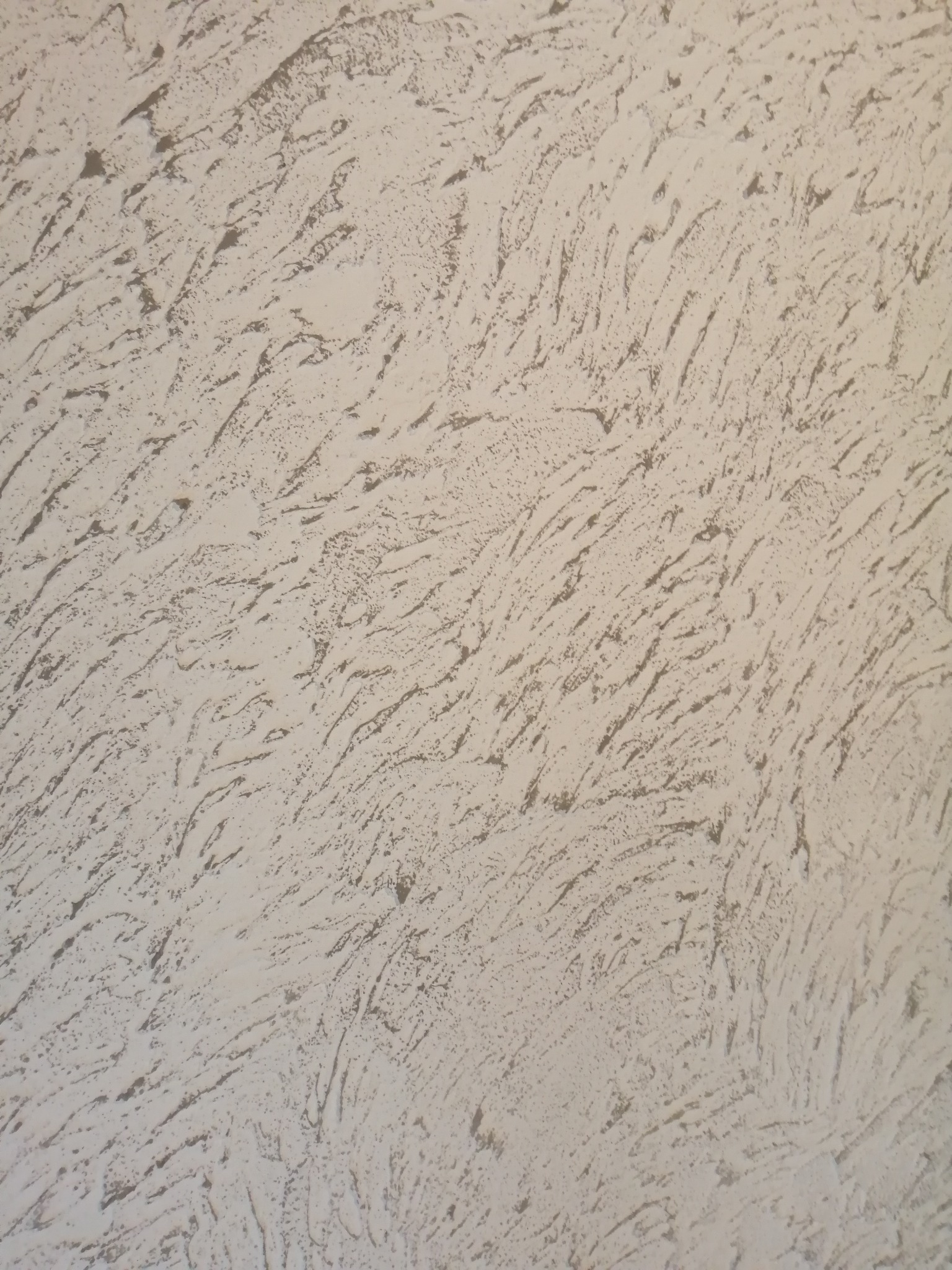 Tekstura ściany pokrytej szarą, dekoracyjną masą z wyraźnymi, nieregularnymi wzorami przypominającymi pociągnięcia pędzlem.