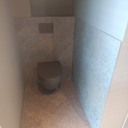 Glazur Usługi Budowlane Marcin Tokarz - Nowoczesna toaleta w zabudowie, szara miska WC i marmurowe płytki na ścianach oraz podłodze, minimalistyczny przycisk spłuczki.