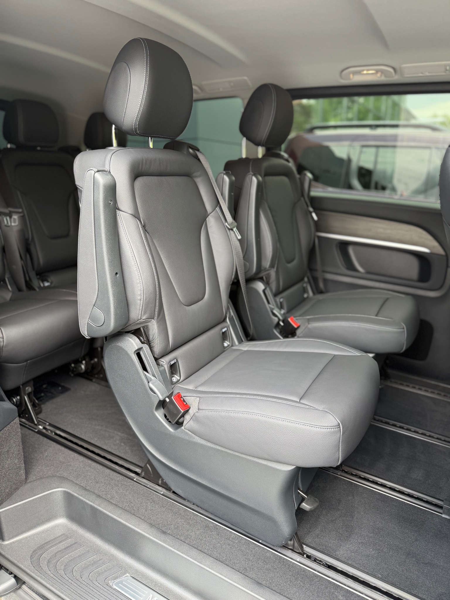 Wnętrze luksusowego busa z szarymi skórzanymi fotelami na szynach, widok z boku. Komfortowy przewóz osób w Ząbkach.