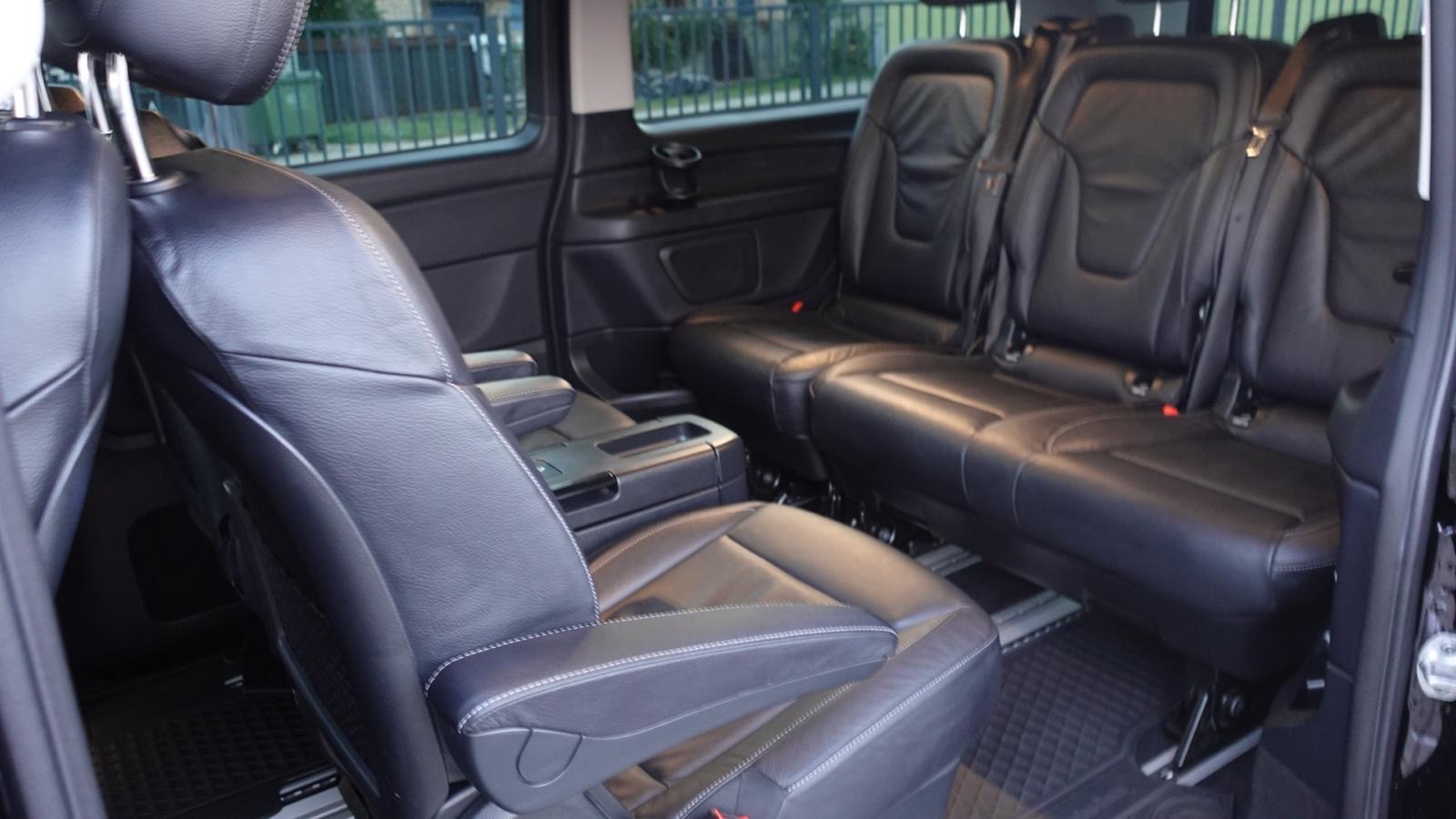 Czarne skórzane fotele w przestronnym wnętrzu vana, widok z boku, oświetlenie dzienne, czysta tapicerka, widoczne zagłówki i podłokietniki.